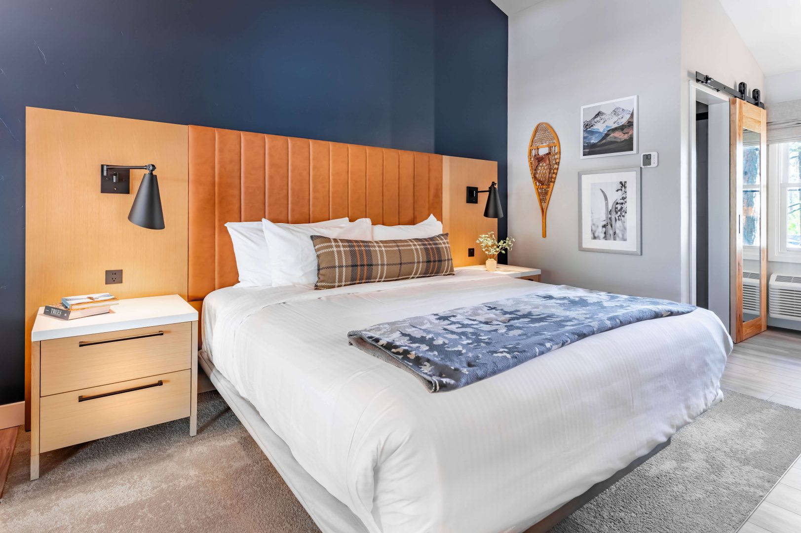 A king bed with white linens and pillows in a spacious High Sierra room at The Incline Lodge.