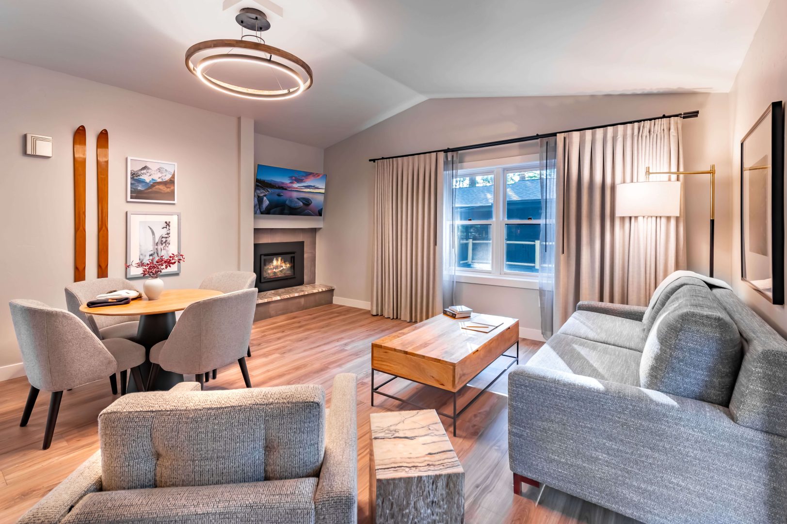 A fireplace, couch, and a table with chairs in the bright and spacious One Bedroom Suite at The Incline Lodge.